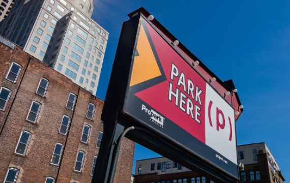 an outdoor billboard sign for a parking lot displaying the words Park Here